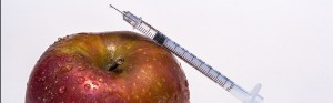 An insulin syringe next to an apple